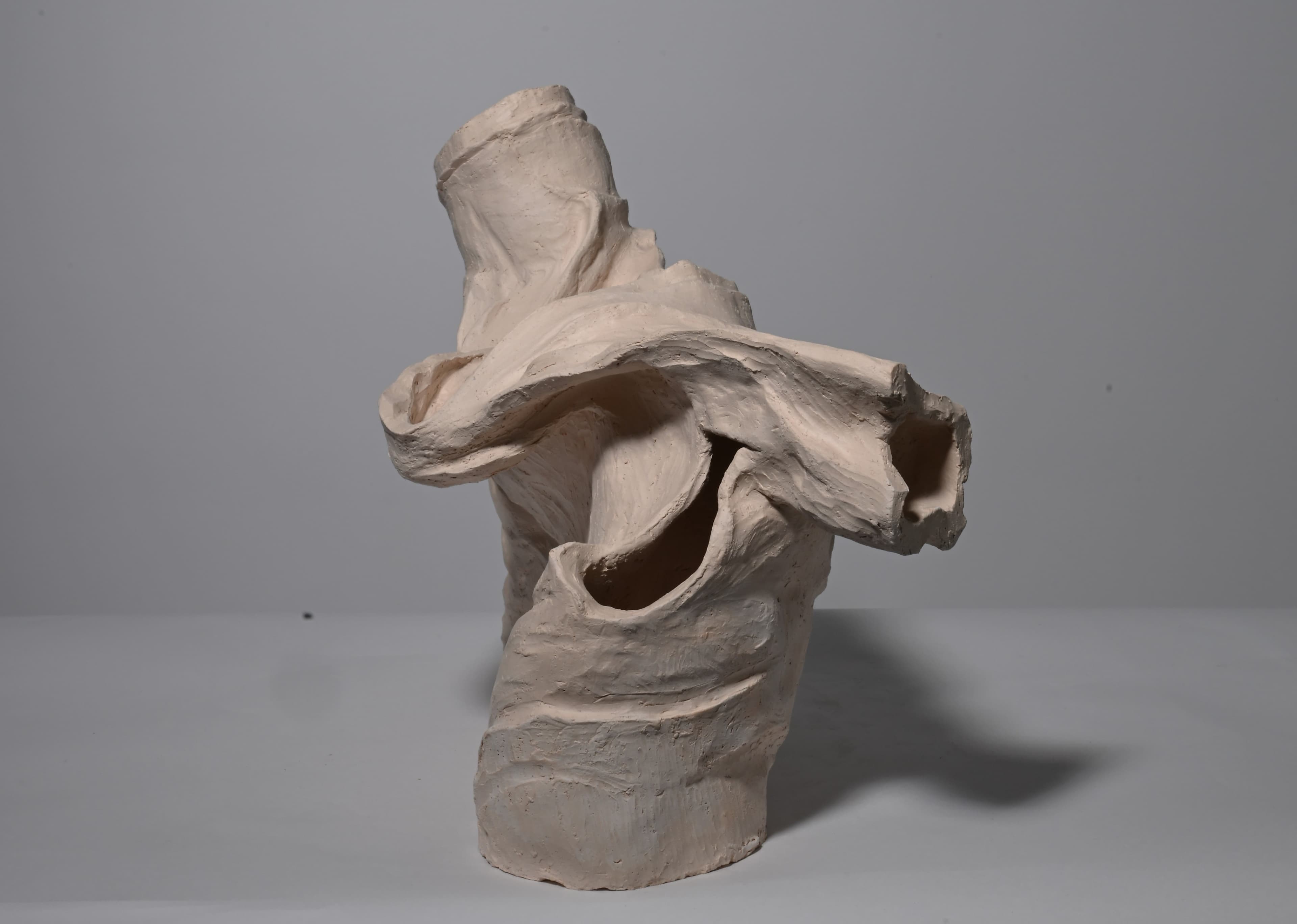 clay sculpture in the shape of wrinkled shirt, bisque fired, side view